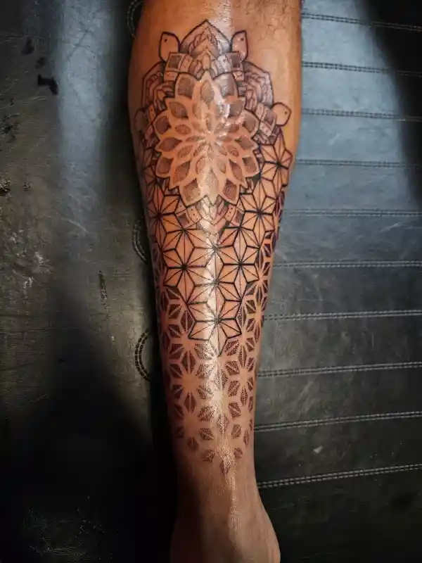 Fine line geometric mandala tattoo on calf with dot work and sacred geometry pattern