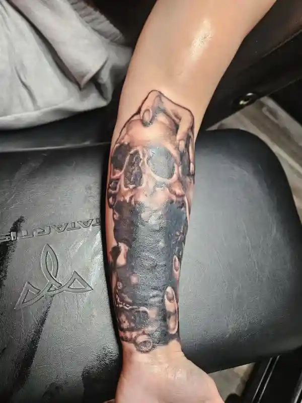 Black and grey cover-up tattoo on forearm blending old ink into a new custom design, Wilmington DE