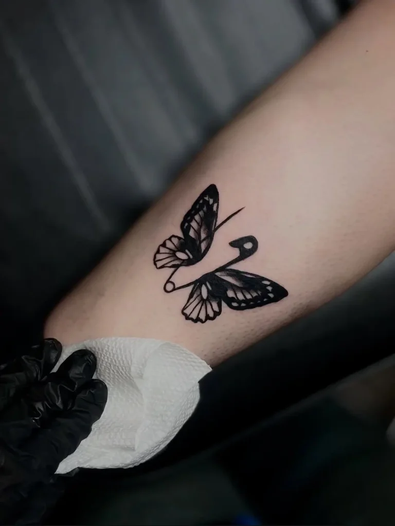 Minimalist butterfly and safety pin tattoo on forearm, Tainted Flesh Body Art North Wilmington DE