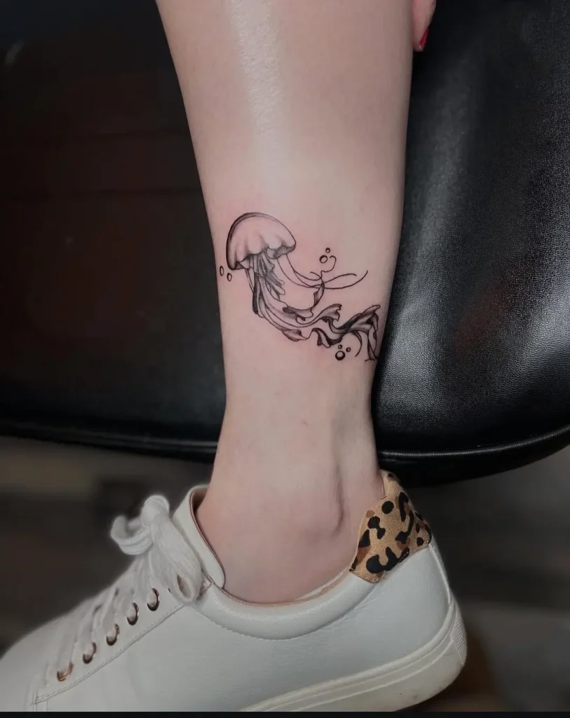 Fine line jellyfish tattoo with flowing tentacles on ankle, Wilmington DE tattoo studio