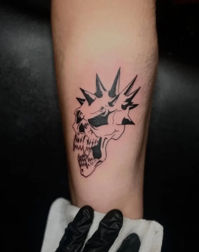 Bold black linework skull tattoo with spiked crown on forearm, Concord Pike tattoo shop