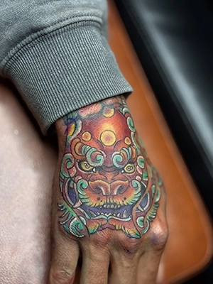 Large custom color tattoo covering forearm with bold linework and shading