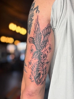 Black and grey sparrow and floral tattoo on the upper arm