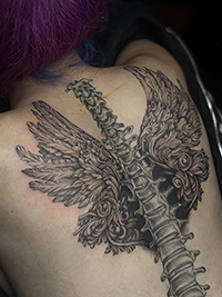Black and grey angel wings and spine tattoo on the upper back