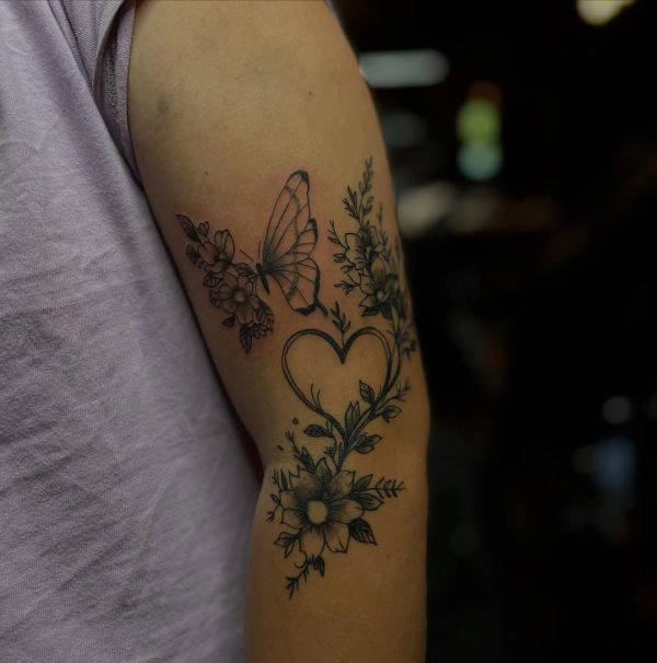 Fine line butterfly, heart, and floral tattoo on the upper arm