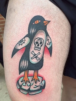 Color traditional penguin tattoo with skull and crossbones design on the thigh