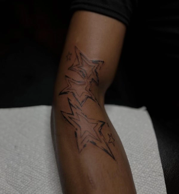 Black linework star tattoo on the inner arm