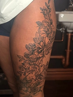 Black and grey floral tattoo covering the thigh