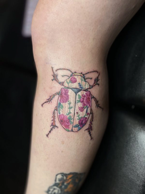 Color floral beetle tattoo on the inner arm