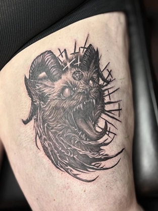 Black and grey demon cat tattoo on the thigh